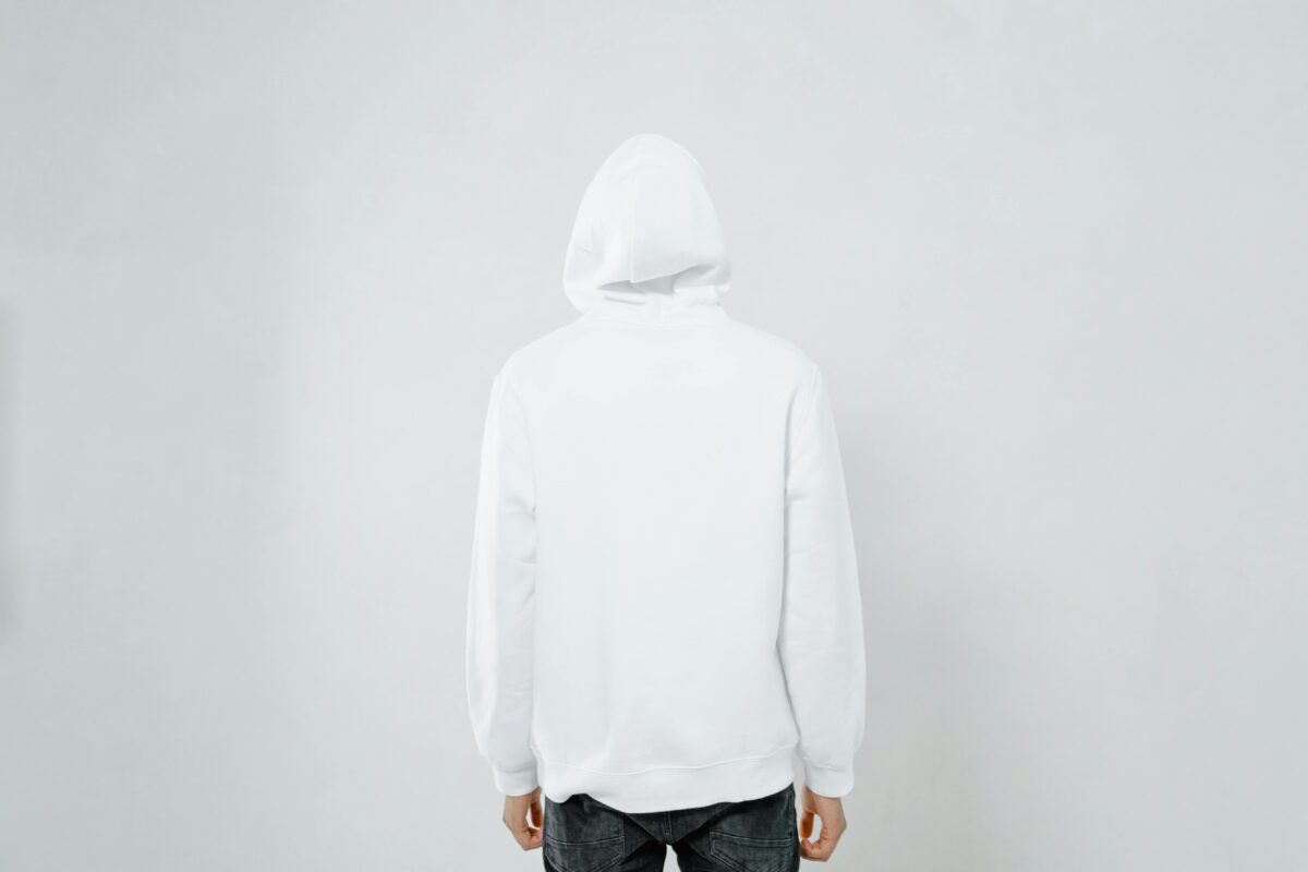 Person wearing a white hoodie facing away against a plain backdrop, offering blank space.